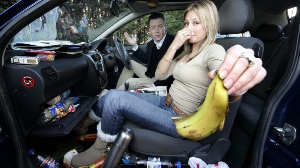 a couple is in a bad smelling car and a girl is through food spills out of the car.