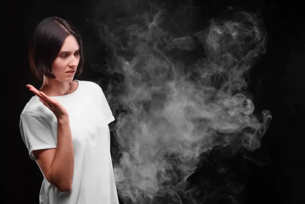 a cloud of smoke and a girl in picture getting annoyed by smoke cloud.