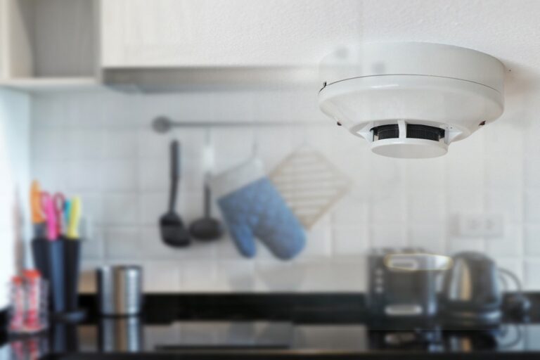 smoke detector on the ceiling with a smoky kitchen in background.