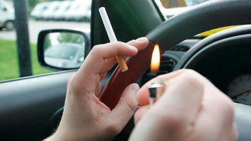 close shot of hands and staring wheel, cigarette and litter in hands.