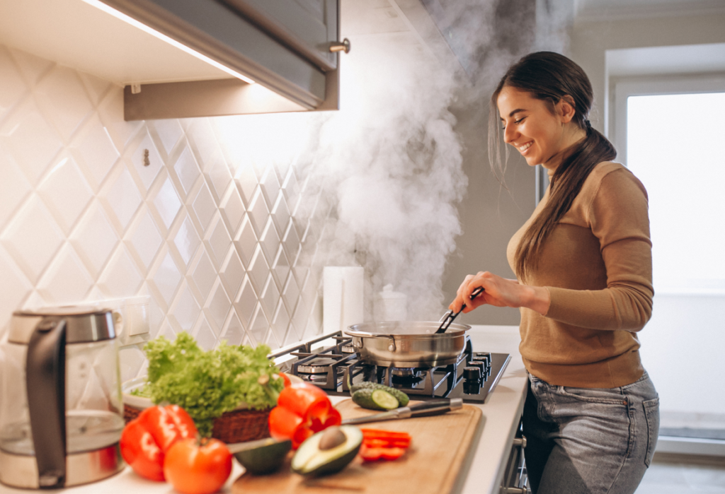 a female is cooking in a happy mode in kitchen and smoke is spreading around.