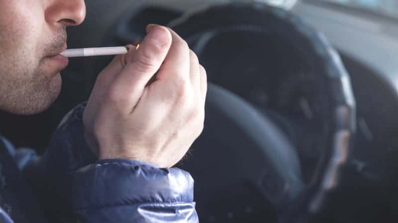 close shot of a man lighting cigarette in a car.