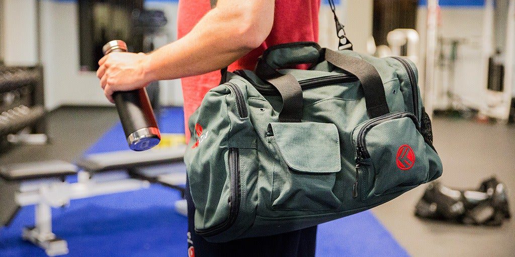 a person holding a bottle in hand and sports bag on his shoulder