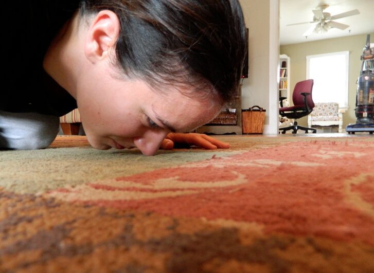 a woman sniffing carpet