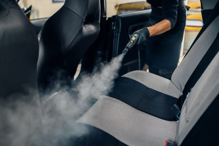 close shot of a person spraying solution on car back seats for odor removal.